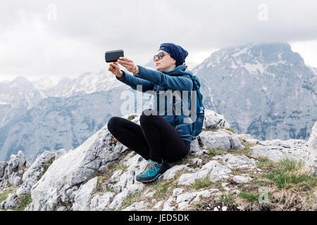 Weibliche Wanderer machen ein Selbstporträt mit ihrem Smartphone mit Hügeln im Hintergrund Stockfoto