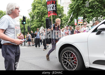 London, UK, 24. Juni 2017. Junge Menschen protestieren vor Downing Street gegen die Tory Regierung, die versucht, eine Allianz mit der DUP erstellen Ein Demonstrant aufsteht vor ein Auto. Stockfoto