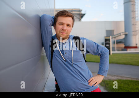 Kaukasische gut aussehender Mann in Freizeitkleidung mit einem freundlichen Lächeln Wand gelehnt Stockfoto