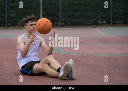 Teenager-Jungen warf einen Basketball aus einer Hand zur anderen auf einem Platz Stockfoto