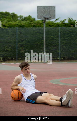 Teenager sitzen auf einem Basketballfeld Stockfoto