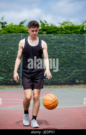 Teenager Prellen einen Basketball auf ein Gericht Stockfoto