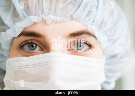 Close-up Portrait der jungen weiblichen Chirurgen Arzt oder Praktikant Schutzmaske und Hut tragen Stockfoto