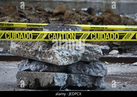 Melden Sie ein Stapel von Platten aus Pflaster und Felsen mit gelben Vorsicht in Englisch und Spanisch Stockfoto