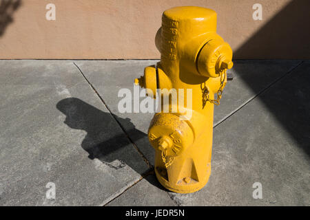 gelber Hydrant auf einem Bürgersteig an einem sonnigen Tag Stockfoto