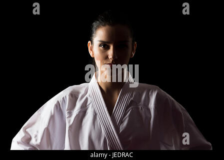 Junge muslimische Frau im traditionellen Kimono üben ihre Karate-Moves - auf schwarzem Hintergrund isoliert Stockfoto