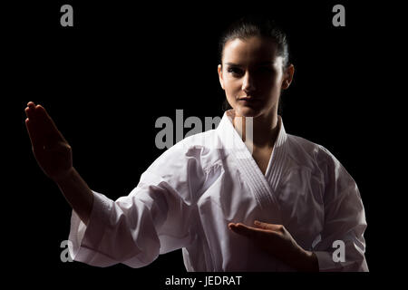 Junge muslimische Frau im traditionellen Kimono üben ihre Karate-Moves - auf schwarzem Hintergrund isoliert Stockfoto