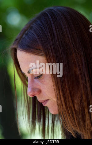 Dies ist ein lebendiges Farbbild eine schöne junge Frau in einem nachdenklichen und nachdenklichen Zustand möglicherweise ein Buch einer Nachricht auf ihr Handy Stockfoto