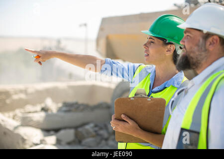 Männliche und weibliche Steinbrucharbeiter vor Ort diskutieren Stockfoto