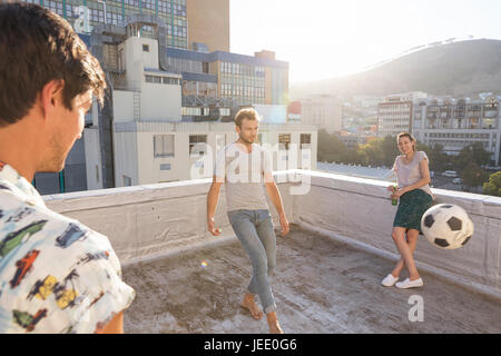 Freunde treffen im Sommer auf der Dachterrasse, Fußball spielen Stockfoto