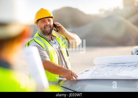 Steinbrucharbeiter vor Ort, am Telefon sprechen Stockfoto