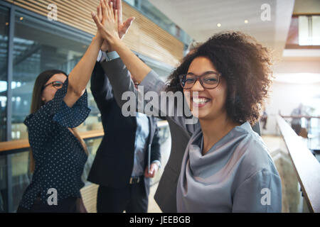 Fröhliche afrikanisch-amerikanischen Büroangestellte geben hohe fünf Kollegen und Blick in die Kamera. Stockfoto