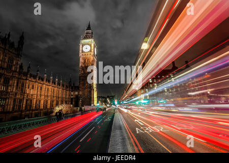 London in der Nacht in der Nähe von Westminster Bridge am Parlament, Big Ben und London Eye sichtbar mit Farbe leuchtet in der dunklen Nacht. London Bus Lichtspuren Stockfoto