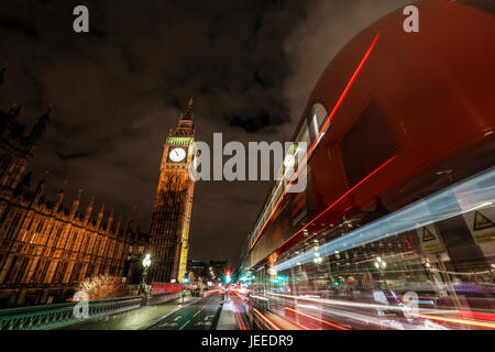 London in der Nacht in der Nähe von Westminster Bridge am Parlament, Big Ben und London Eye sichtbar mit Farbe leuchtet in der dunklen Nacht. London Bus Lichtspuren Stockfoto