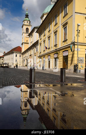 Uhr und Bell Tower of St. Nicholas Catholic Church Ljubljana Kathedrale spiegelt sich in einer Pfütze auf Cyril Methodius Square Ljubljana Slowenien Stockfoto