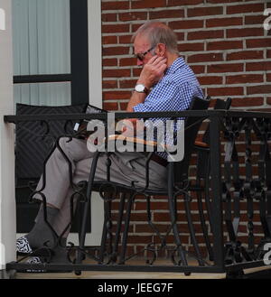 Älterer Mann liest ein Buch auf der veranda Stockfoto