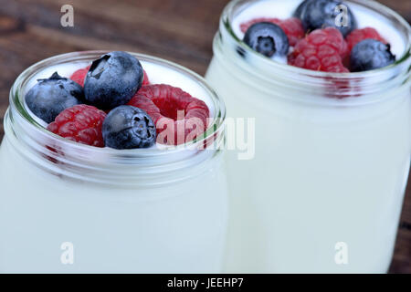 Gläser mit Joghurt und verschiedene Beeren auf Holztisch Stockfoto