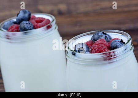 Gemischte Beeren mit Joghurt im Glas Gläser auf hölzernen Hintergrund Stockfoto