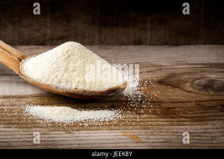 Bio Grieß oder Couscous Weizen in Holzlöffel auf hölzernen rustikalen Hintergrund. Stockfoto