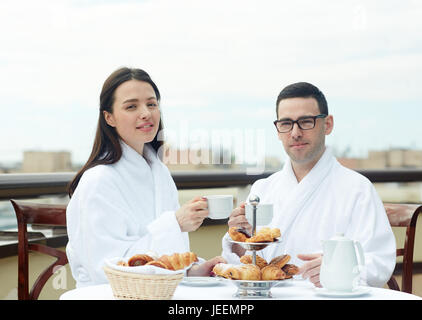 Brautpaar mit Tee mit frischen Brötchen auf Balkon Stockfoto