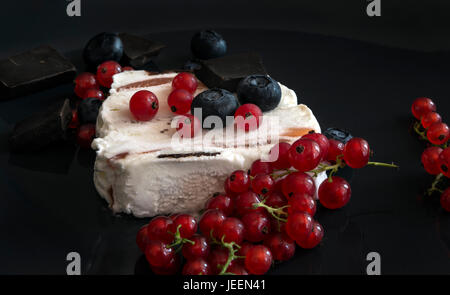 Eis mit dunkler Schokolade, Heidelbeeren und roten Johannisbeeren auf schwarzem Hintergrund Stockfoto