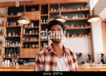 Porträt von glücklicher junge Mann stehend in einer Cafébar. Hübscher junger Mann in einem Café. Stockfoto