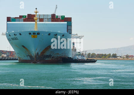 Das riesige COSCO Ningbo Containerschiff orientiert sich in Liegeplatz J270 am Pier J an AmNav Traktor Schlepper Unabhängigkeit am Long Beach Containerterminal. Stockfoto