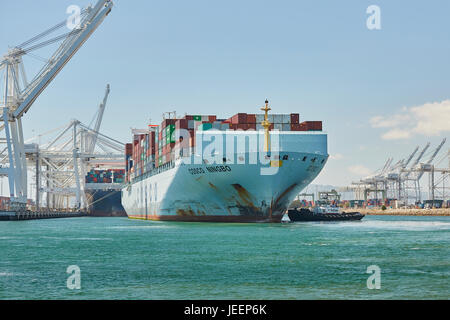 Das riesige COSCO Ningbo Containerschiff in Liegeplatz J270 am Pier J AmNav Traktor Schlepper Unabhängigkeit am Long Beach Containerterminal orientiert, Stockfoto