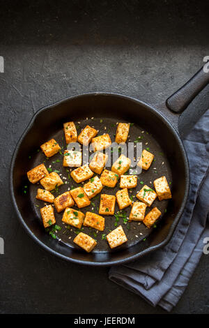 Gebratener Tofu mit Sesam und Gewürzen auf gusseisernen Pfanne, Textfreiraum. Gesunde Zutat zum kochen Vegan vegetarisch essen. Gebratener Tofu über bla Stockfoto