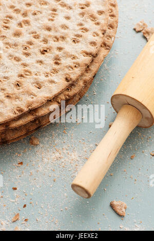 Schwedisches Fladenbrot in Nahaufnahme. Rundes Knäckebrot und Nudelholz am Küchentisch. Stockfoto