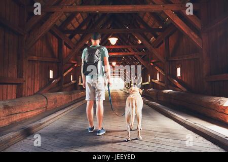 Junge Touristen mit seinem Hund in die überdachte Brücke über den Fluss in Radosov, Tschechische Republik Stockfoto