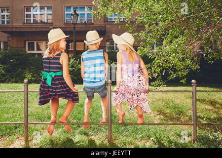 Sommertag in der Stadt. Die drei Geschwister an der Reling sitzen und entspannen. Stockfoto