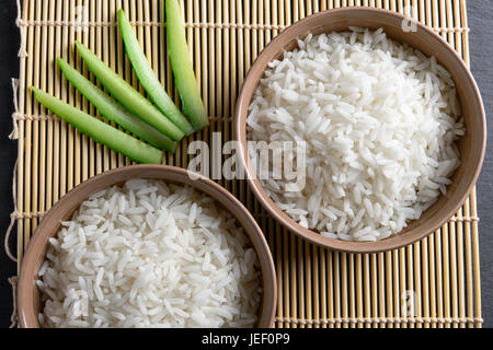 Ansicht von oben: gedämpfte gekochten weißen Basmati-Reis in Runde Keramik Schalen über schwarzen Stein Stockfoto