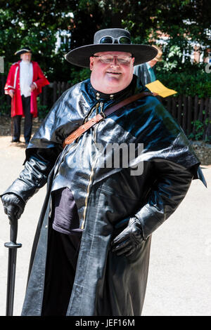 Steampunk, großen kaukasischen Mann, 40s, in schwarzem Leder Mantel und Hut mit Krempe Schutzbrille. Lächelnd. Stockfoto