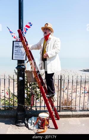 Herr William Thompkins, Anzünder, Charles Dickens Charakter, Geschichte. Das Tragen von weißen Mantel und Strohhut, steht auf Ladder gegen Licht mit Union Jack. Stockfoto