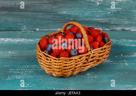 Himbeere mit Heidelbeere im Korb auf einem alten blauen Brett Stockfoto