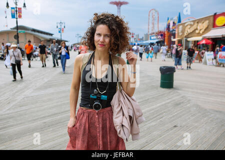 Cool, schöne Frau mit einer Diana Lomography Kamera hält den Hals in Coney Island Promenade während Sommerwochenende, Brooklyn, USA Stockfoto