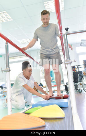 Mann tut Lauftraining mit Physiotherapeut /-in Pflegeheim Stockfoto