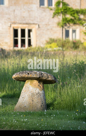 Staddle Steinen vor einem Haus in dem Dorf Wyck Rissington in den späten Abend Juni Sonnenschein. Cotswolds, Gloucestershire, England Stockfoto