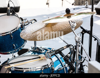 blaue Drumset mit zwei hölzernen Drumsticks drauf. Musikinstrumente auf der Bühne, bereit für den Auftritt. Stockfoto