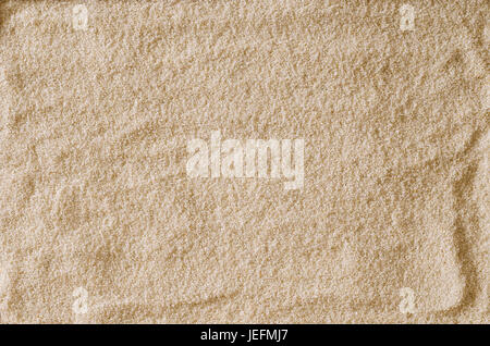 Rau und uneben leer Sandoberfläche als Hintergrund oder als Textur verwenden. Hell braun und Ocker gefärbt Sandkörner. Makrofoto Nahaufnahme von oben. Stockfoto