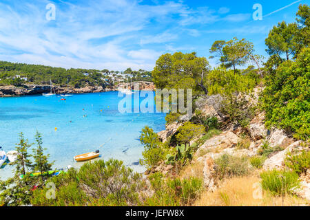 Grünen Treeson Klippe Felsen mit Blick auf Bucht von Cala Portinatx mit azurblauen Meerwasser, Insel Ibiza, Spanien Stockfoto