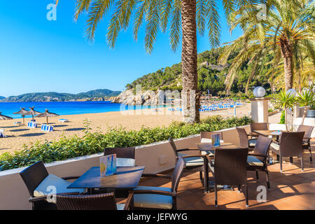 Bucht von CALA SAN VICENTE, Insel IBIZA - 19. Mai 2017: Hotel Bartische am Strand mit Palmen in Cala San Vicente Bucht, Insel Ibiza, Spanien. Stockfoto