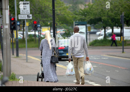 Asiatische Familie Flüchtling auf Straße in der UK alltägliche Szene Lidl Einkaufstaschen tragen Hijab Schal gekleidet Stockfoto