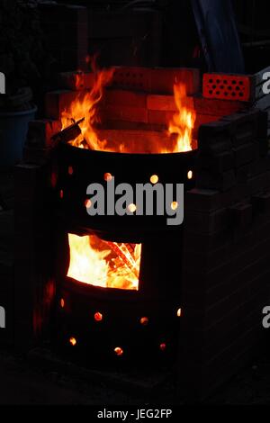 Gartenbrand in einer Öltrommel. Feuer der orangen Flamme Nahaufnahme in der Nacht. Exeter, Devon, Juni 2017. Stockfoto