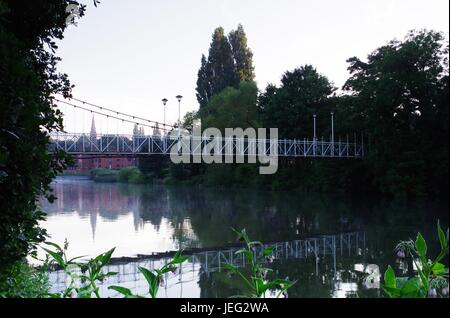 Karottenhosenträger Wehr Hängebrücke über den Fluss Exe und der Turm der Kirche St. Leonard im Morgengrauen. Exeter, Devon, UK. Juni 2017. Stockfoto