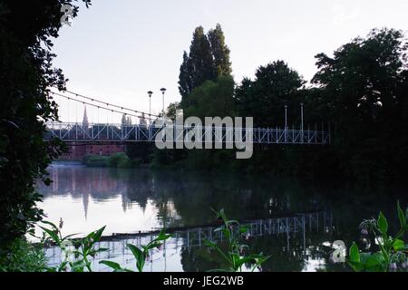 Karottenhosenträger Wehr Hängebrücke über den Fluss Exe und der Turm der Kirche St. Leonard im Morgengrauen. Exeter, Devon, UK. Juni 2017. Stockfoto