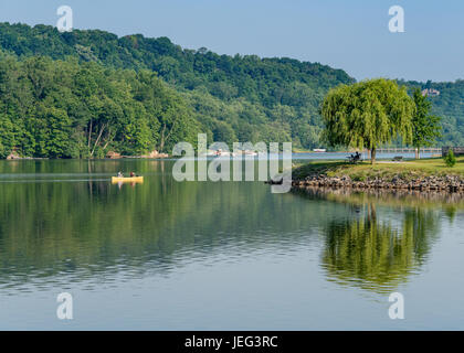 Paar-paddeln in gelben Kanu auf Baum gesäumten See Stockfoto