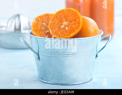 Mandarinen in Metallschale und auf einem Tisch Stockfoto