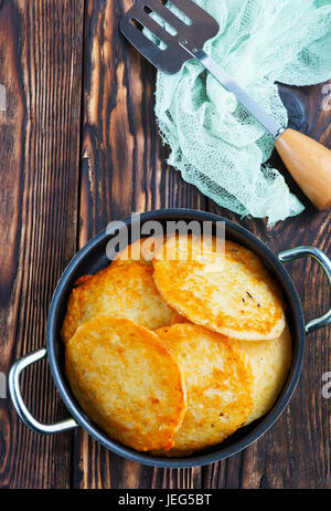 Kartoffelpuffer in der Pfanne und auf einem Tisch Stockfoto